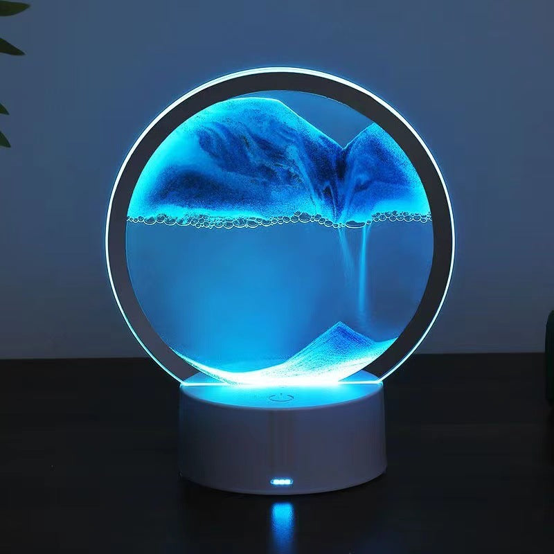 Round blue illuminated moving-sand ambient lamp on a white base